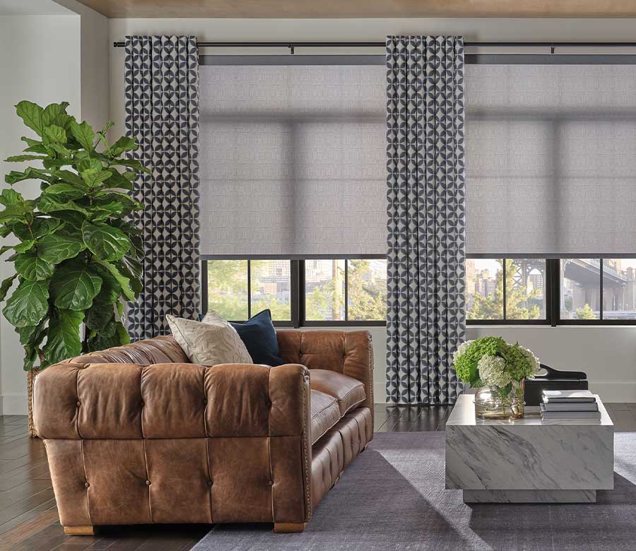 designer roller shades with drapery in living room with black window trim