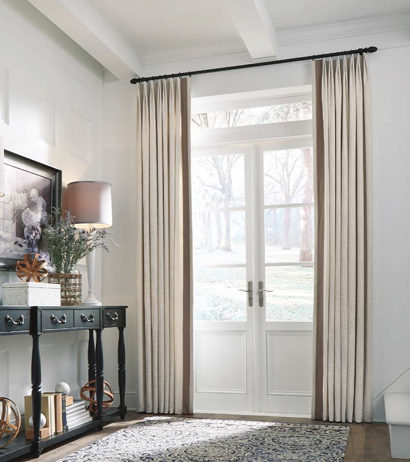 cream colored drapery on side of white glass door with black hardware