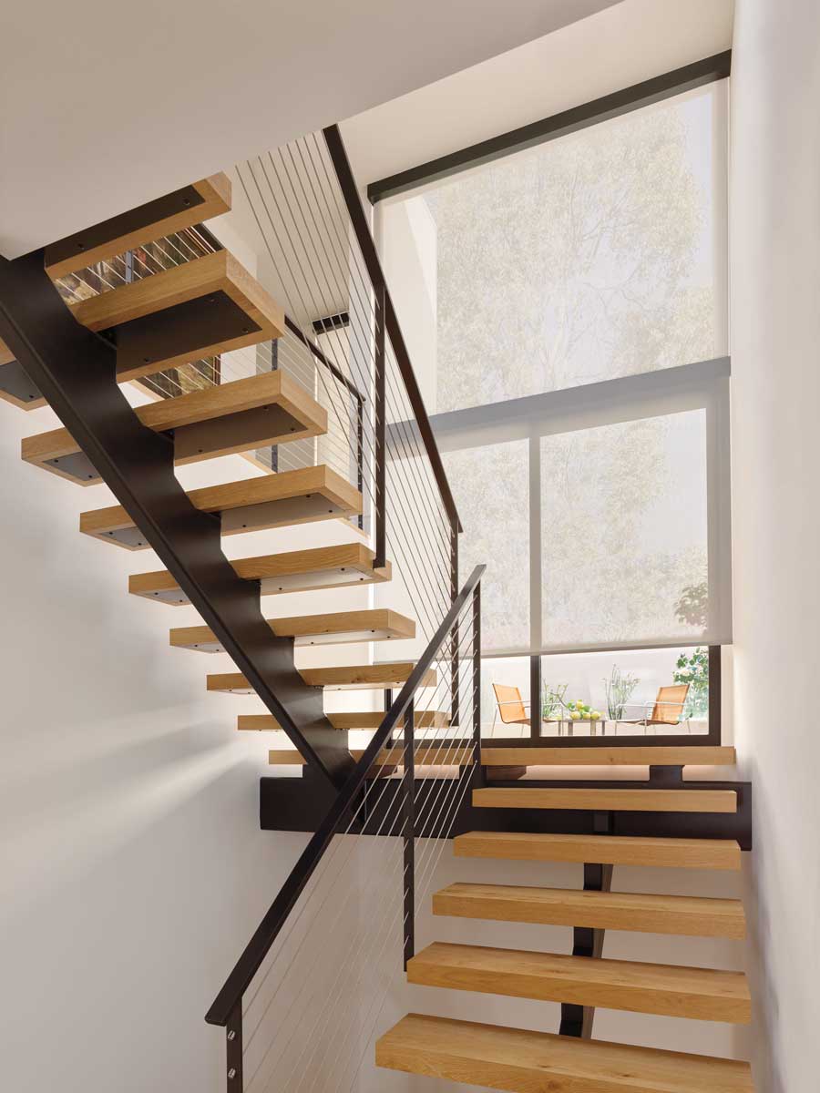 Stair landing with white solar roller shades for window coverings and black framed stairs