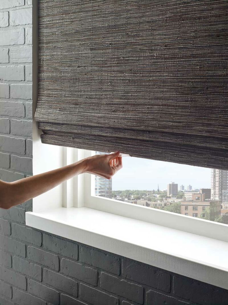 hand pulling down on window shade on window