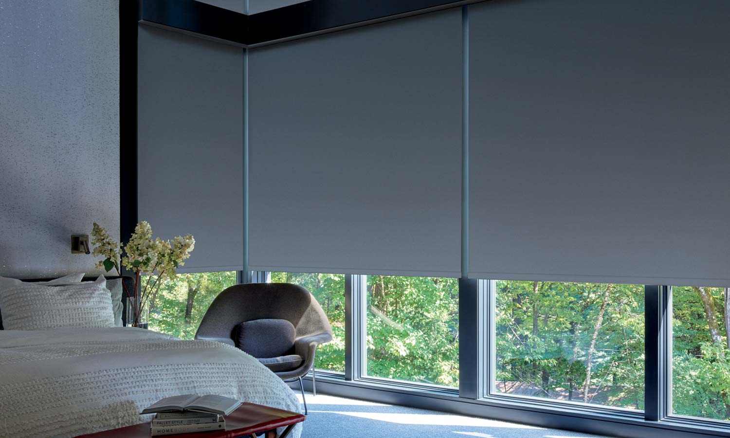 Room-darkening roller shades covering large bedroom windows